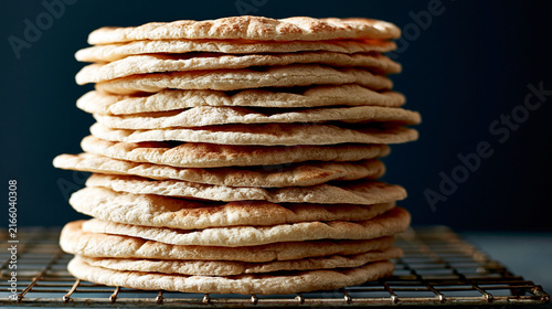 Stack of freshly baked flatbreads on a metal cooling rack with baked goods