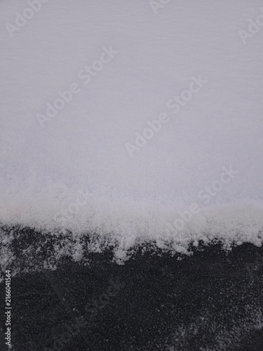 Obraz na płótnie Snow blankets a dark, textured surface below