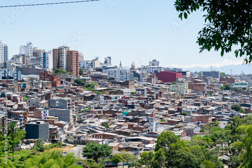 Aerial cityscape of Pereira, Colombia, with dense neighborhoods, lush vegetation, mountains and an urban river valley
