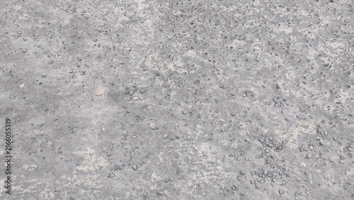 Close-up of a rough grey concrete floor surface texture with porous details. Concept of industrial architecture, weathered building material, urban background, and construction.