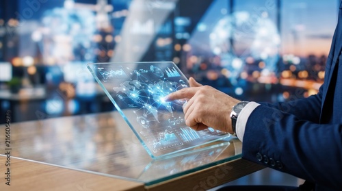 Close up of a businessman using a transparent futuristic tablet device displaying a glowing global network map and data analytics, representing international business connectivity