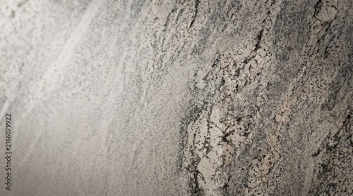 A high-resolution, detailed close-up photograph of a polished granite stone slab surface. The stone exhibits a complex and natural speckled texture, primarily composed of interlocking grey, white, and