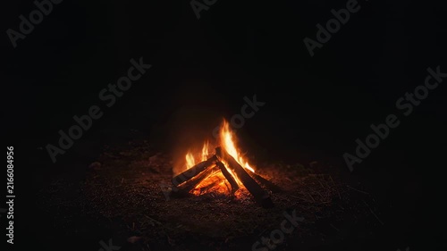 Nature - A cozy bonfire crackling in the dark night outdoors with bright flames burning wooden logs on the ground