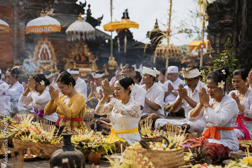 balinese hindu people praying in traditional clothing during a sacred temple ceremony in bali