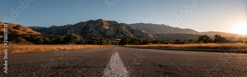 Asphalt road leading through a mountain valley at sunrise