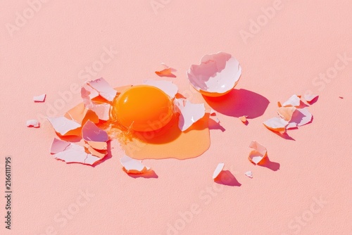 Broken egg yolk on pink surface (1)
