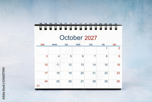 October 2027 Monthly desk calendar on vintage wall, Front view.