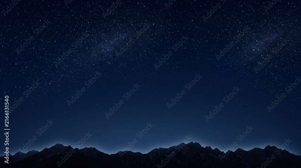 Fototapeta premium Beautiful starry night sky over dark mountain peaks. A breathtaking deep space background with stars and nebula.