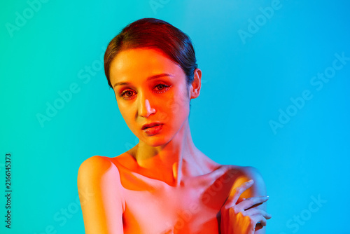 Canvastavla Young woman beauty portrait with colorful neon lighting on blue background
