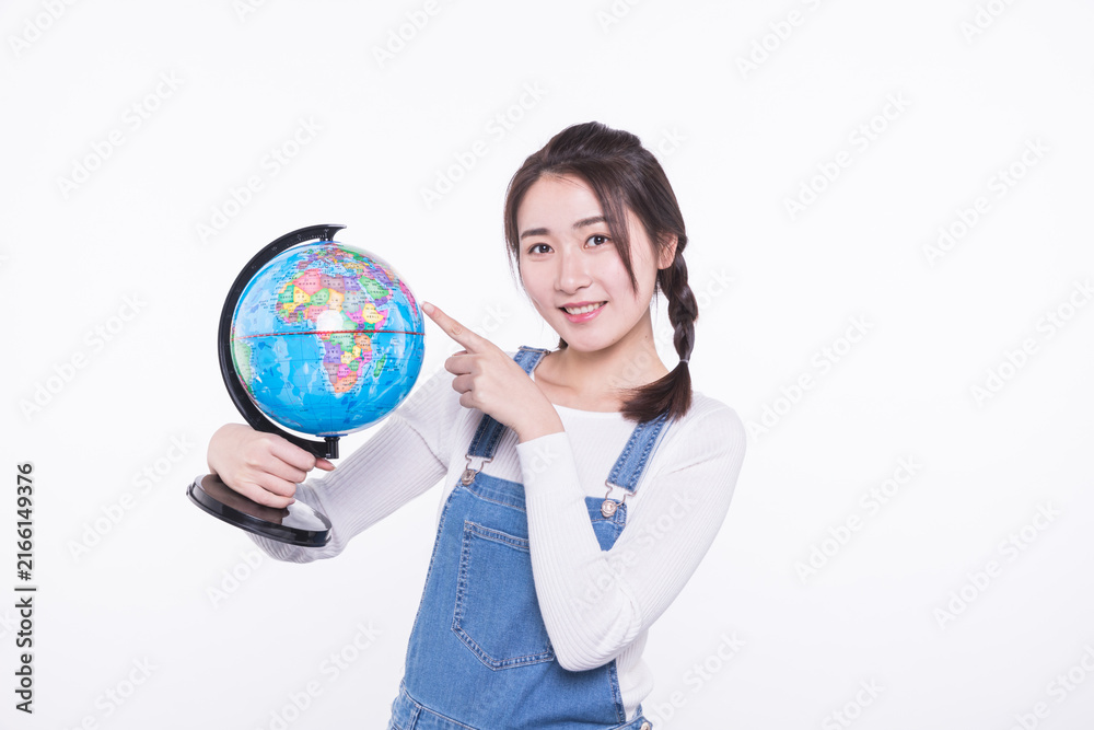 Fototapeta premium Young woman pointing at a globe isolated on white