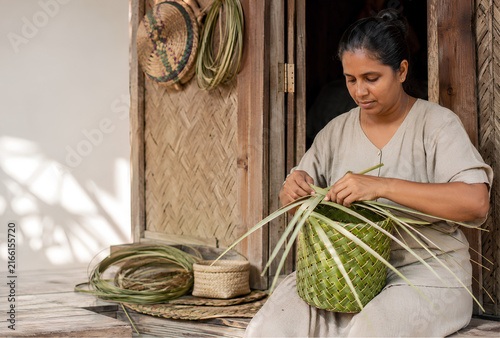 Woman weaving a basket from palm leaves