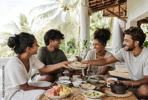 Four friends sharing a meal outdoors on a sunny day
