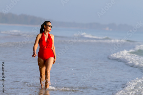 Woman with red swimsuit walk smile on beach