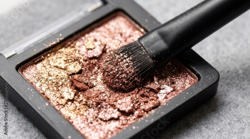 Close-up of a makeup brush dipping into a crushed shimmer eyeshadow palette