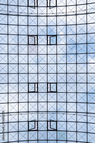 Canvastavla Untersicht auf eine moderne Glasdachkonstruktion mit geometrischem Muster, offene Fenster und blauen Himmel