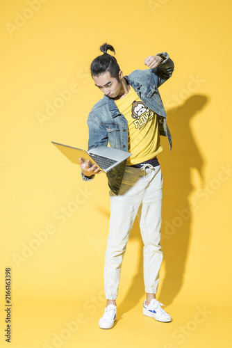Bild auf Leinwand Young man reacting to laptop on yellow background