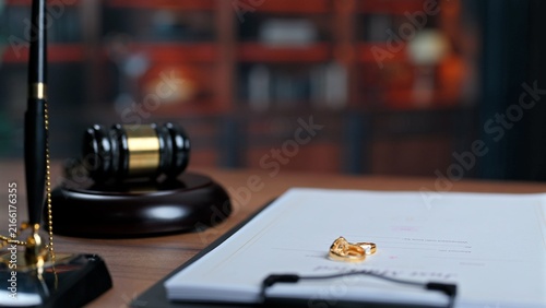 Photography Divorce proceedings feature wooden judge gavel beside signed legal paper, placing official divorce settlement agreement near traditional courtroom gavel before finalizing legal divorce