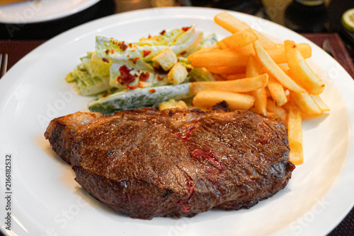 Quadro su tela Grilled steak with fries and salad on a white plate