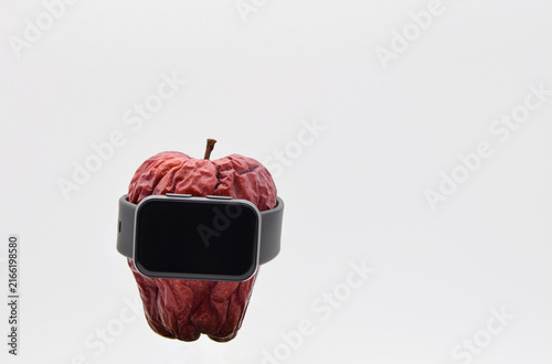 Fotografie Tired worn-out red apple wearing a smart watch