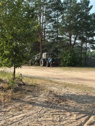 Картината върху платно A dark tractor parked on a sandy dirt road with deep tire tracks