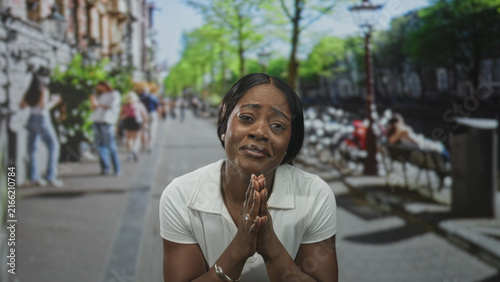 Photography Woman raises clenched fists and smiles broadly in white shirt on a busy urban street with benches and trees; joy triumph celebration