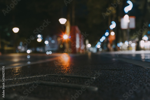 Nighttime urban street in Tokyo, Japan — wet asphalt reflects glowing streetlights and blurred city