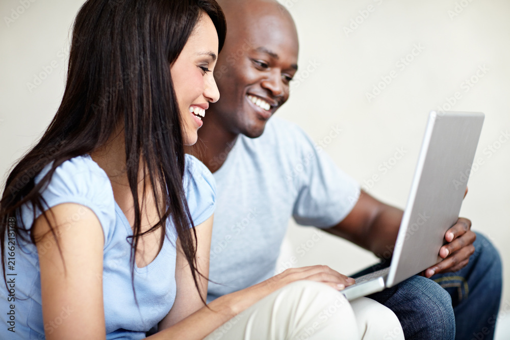 Fototapeta premium Couple, laugh and chill with laptop in home, online and watching movie with partner or subscription. Interracial relationship, love and happy people with tech, relax and streaming funny film in house