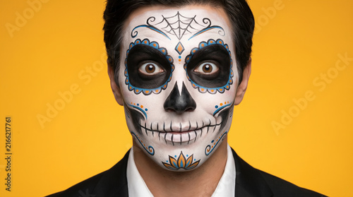 Man with sugar skull makeup looking at camera. Halloween  Dia de los Muertos  costume party  festive celebration.