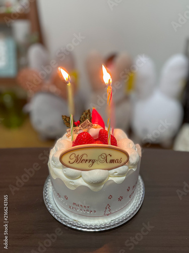 ろうそくに火を灯したクリスマスケーキ