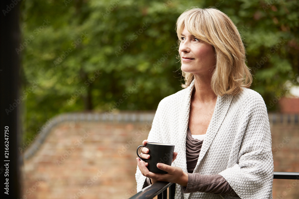 Fototapeta premium Coffee, thinking and woman on balcony of holiday home for morning break, relax or space. Smile, cup and reflection of mature person on terrace of apartment for memories, nostalgia or planning