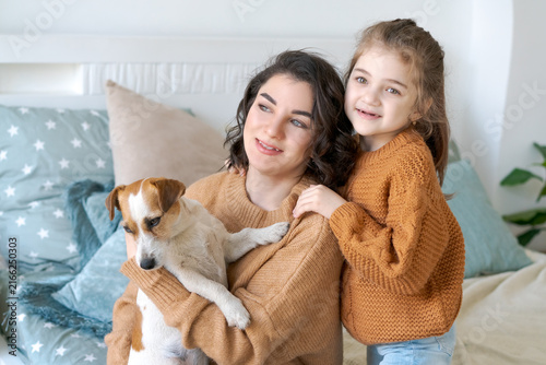 фотографія Caucasian mom and her daughter holding a small jack russell terrier puppy at hom