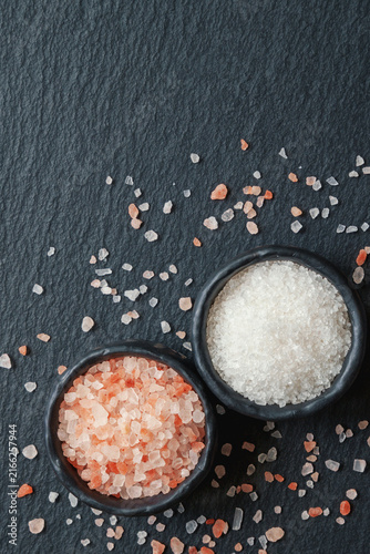 Himalayan pink salt and white cooking salt on black table. Flat lay. Copy space