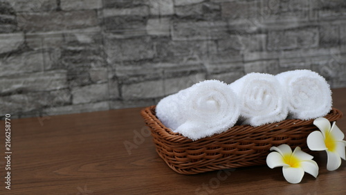 Fotografie Three clean white towels were rolled and neatly arranged in a wicker basket, with frangipani flowers adorning the side