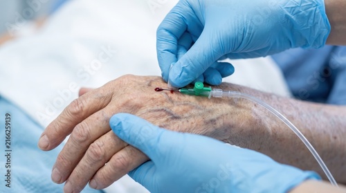 Nurse inserting an IV line with needle into a patient vein for fluid and medicine administration in an emergency ward.