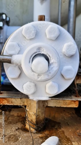 Close-up of frozen pipe flange emitting cold steam and thick ice formation in cryogenic liquid facility