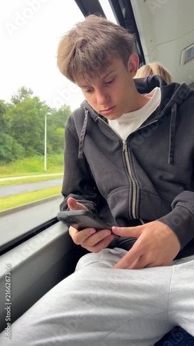 Teenager passenger browsing smartphone while traveling by city bus on a summer day
