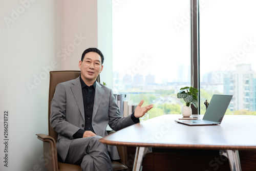 Canvas Print Confident businessman sitting in modern office with city view