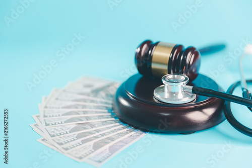 Bild auf Leinwand Judge gavel and stethoscope beside US dollar banknotes on blue represent medical
