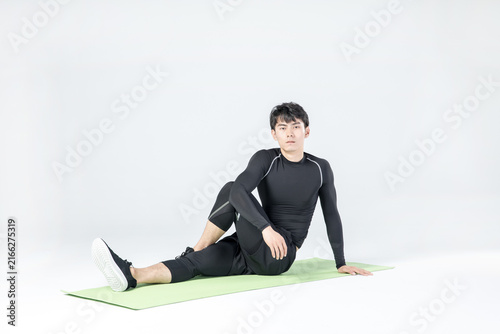 Athletic man stretching on yoga mat in studio