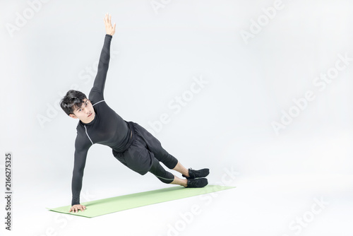 Athletic man doing side plank exercise on yoga mat in studio