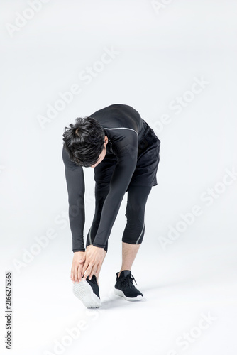 Athletic man stretching and touching foot during warm up exercise in studio