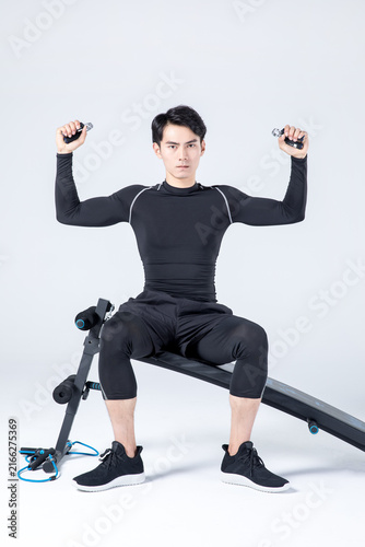 Young man using hand grippers on incline bench during fitness workout