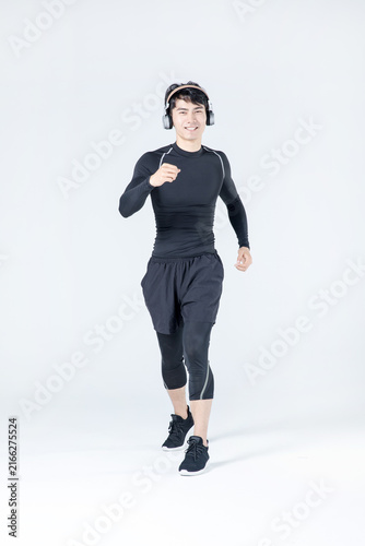 Young athletic man jogging with headphones in studio