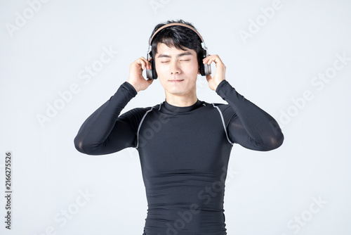Young athletic man listening to music with headphones in sportswear
