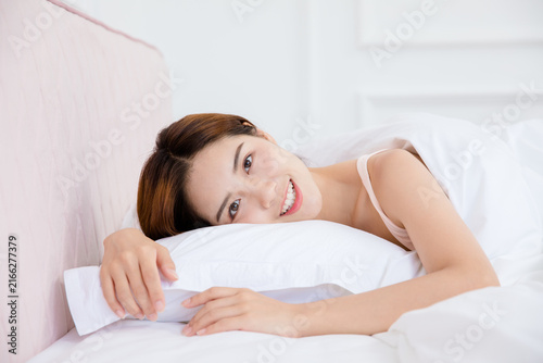 Bild auf Leinwand Smiling young woman relaxing in bed at home