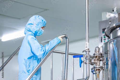 Cleanroom worker checking industrial processing equipment in manufacturing facility