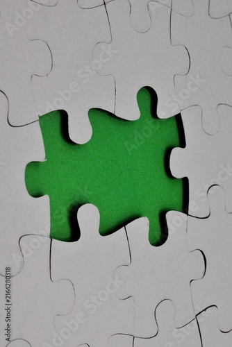 White jigsaw puzzle assembly featuring a missing center piece that exposes a vivid green background underneath.