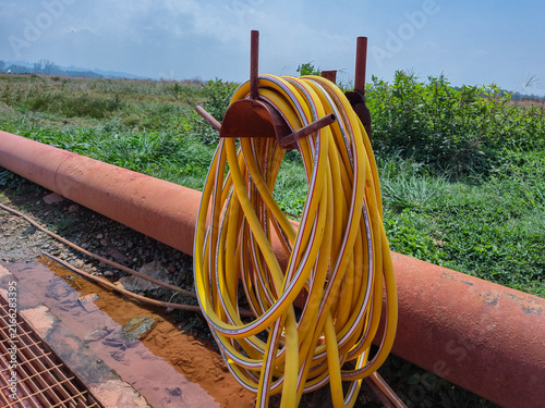 Obraz na płótnie Yellow high pressure water hose coiled on stand at outdoor industrial and agricu