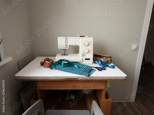 Foto Idle sewing machine on organized worktable with fabric, ribbons, and tools