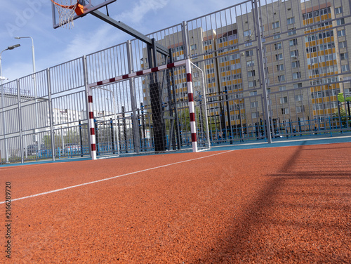 Fotografía Unoccupied outdoor basketball court with hoop, fence, and high-rise backdrop in urban setting